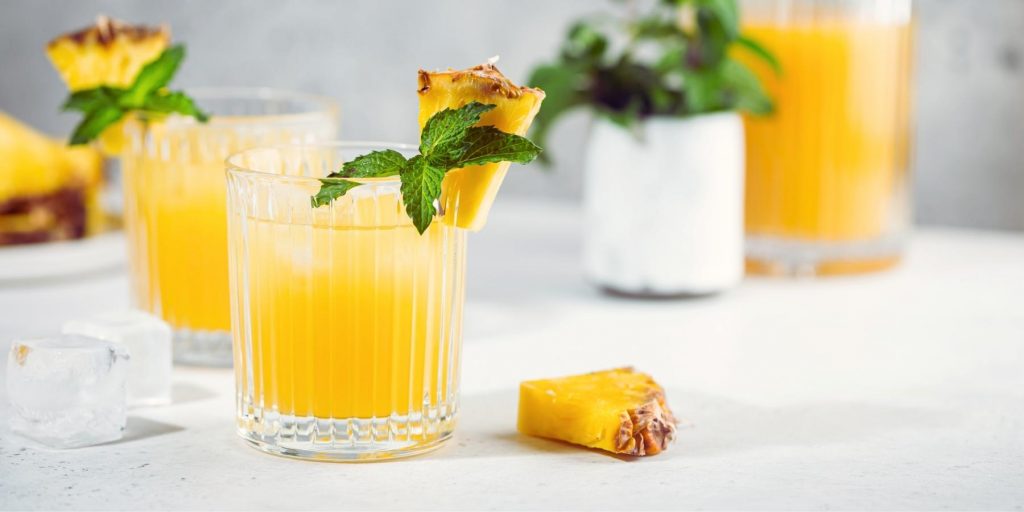 Two refreshing Pineapple Vodka cocktails on ice with mint garnish