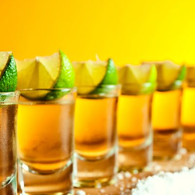 Row of tequila shots with salt and lime wedges