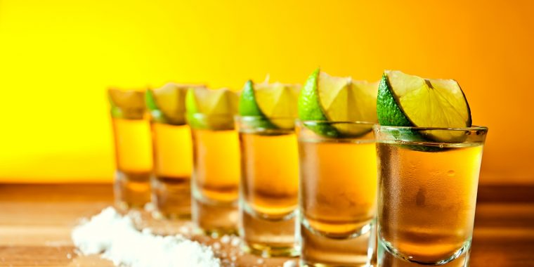 Row of tequila shots with salt and lime wedges