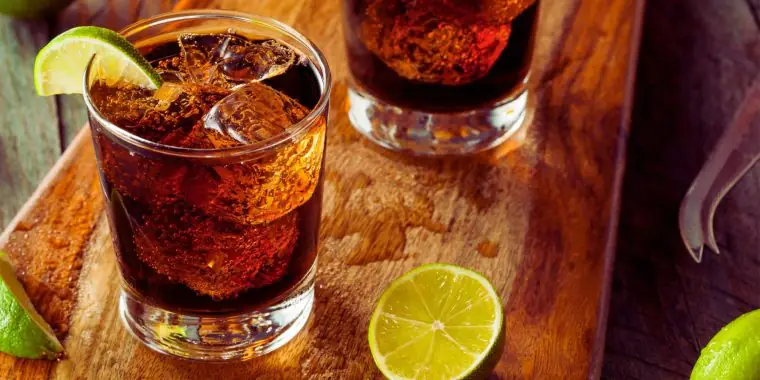 A Vodka and Coke cocktail served on ice with a twist of lime