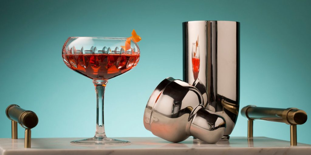 Close up of a glass of Tierra del Fuego cocktail on a serving platter along with a silver cocktail shaker