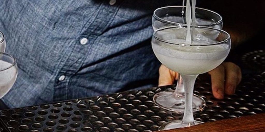 Close up shot of a bartender at the Dutch Kills cocktail bar in NYC split pouring two Daiquiries at Happy Hour