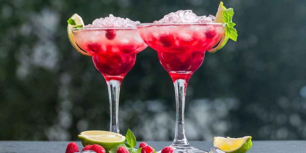 Close up of two Raspberry Margarita cocktails in a bright outdoor setting