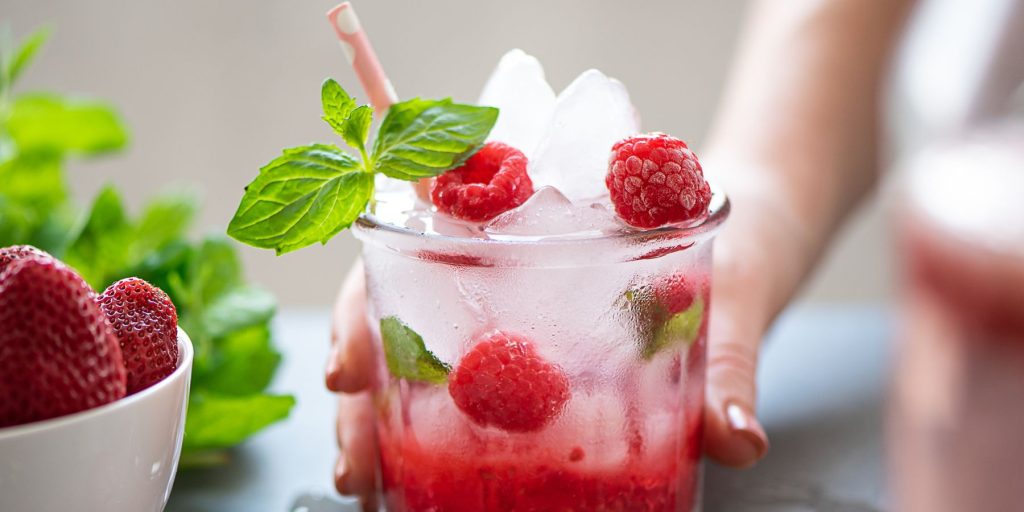 Close up of a woman's hand holding a refreshing Raspberry Mojito