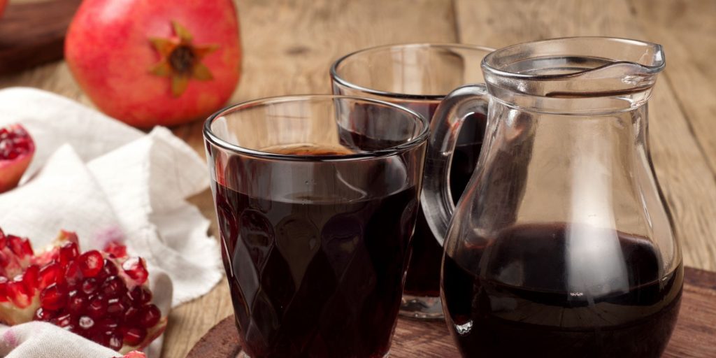 Close up of a jug and two glasses of fresh pomegranate juice
