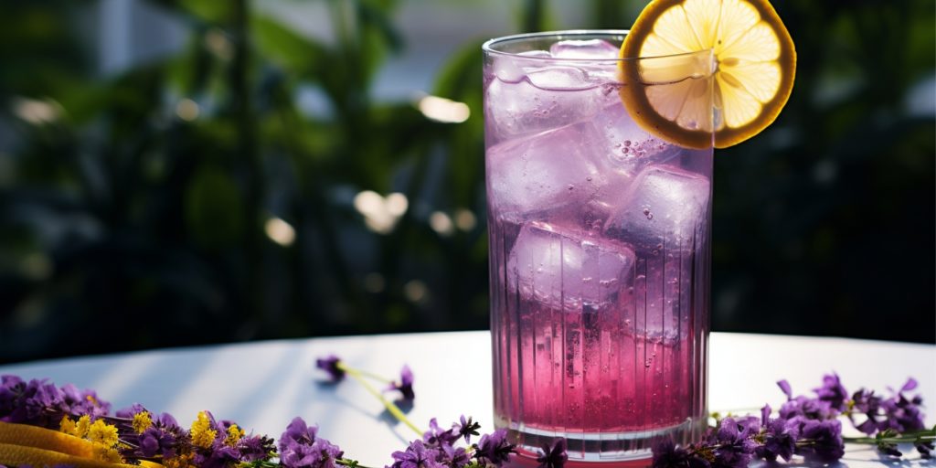 Purple Viking cocktail in garden setting with fresh lemon garnish