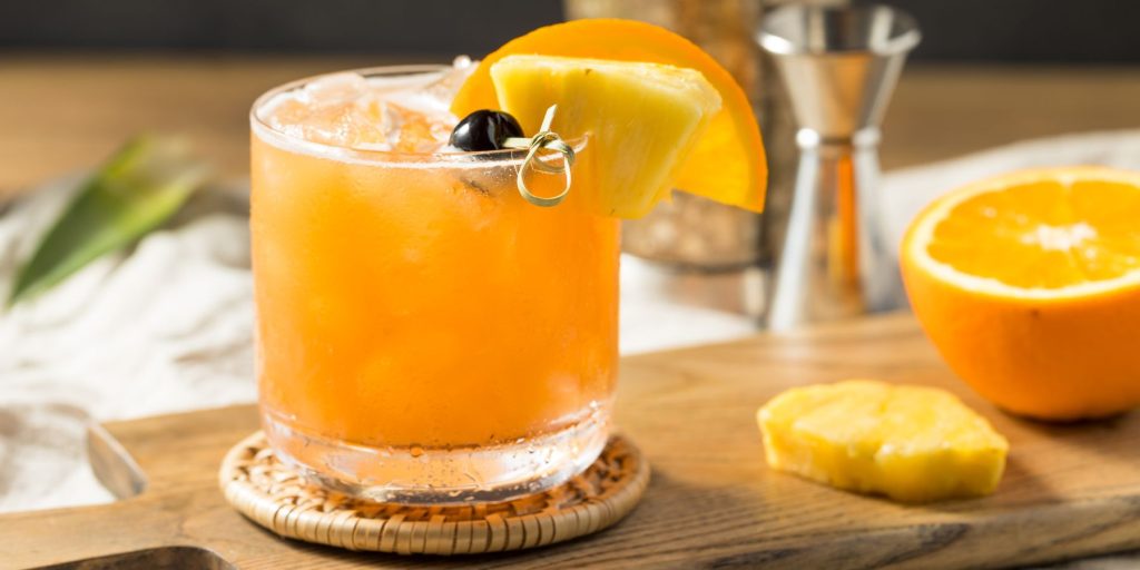 Close up of a Rum Runner cocktail garnished with pineapple and a slice of orange