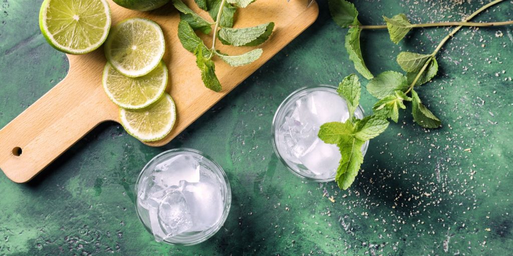 Top view of Mojito ingredients displayed on a blue marble surface in a bright home kitchen