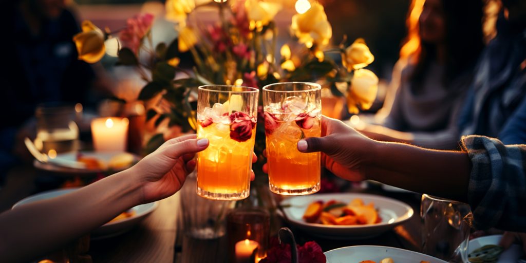 Close up of the hands of two friends clinking Thanksgiving mocktails against a festive and inviting fall decorated background