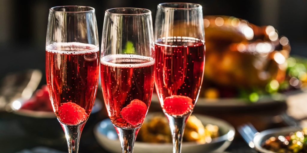 Three Kir Royale cocktails in flute glasses with raspberry garnish