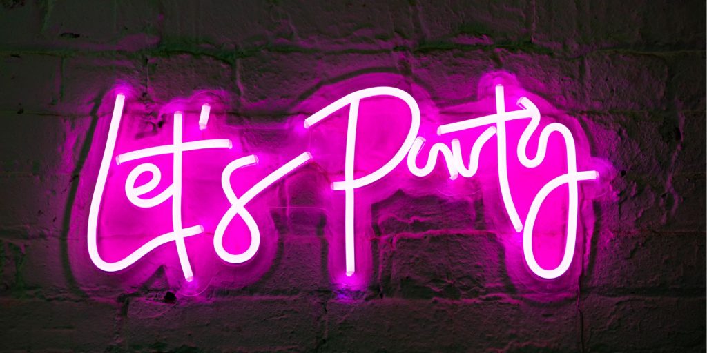 Close up of a neon sign reading 'let's party' in neon pink