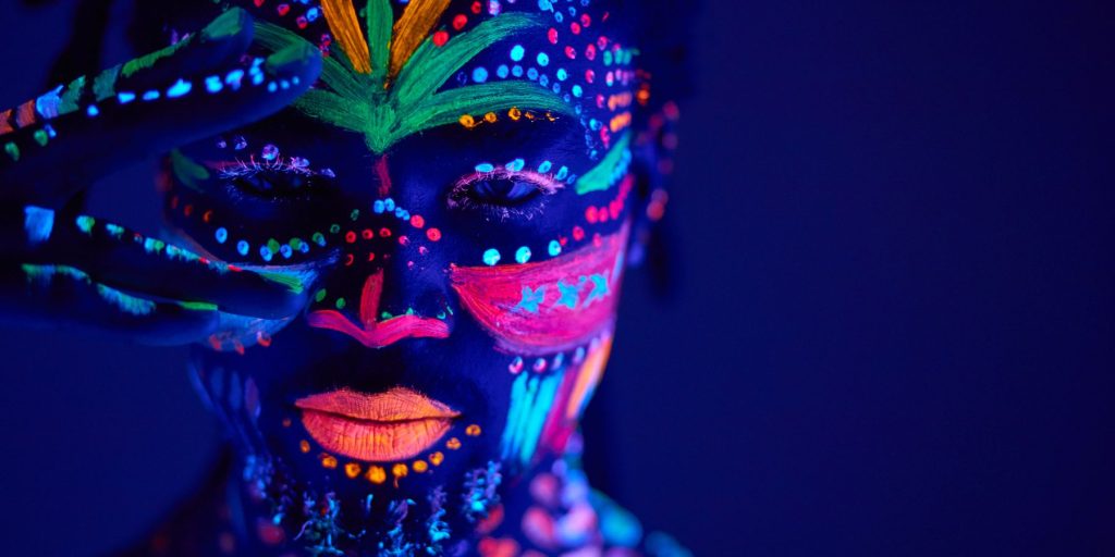 Close up of a man wearing neon makeup for a glow party