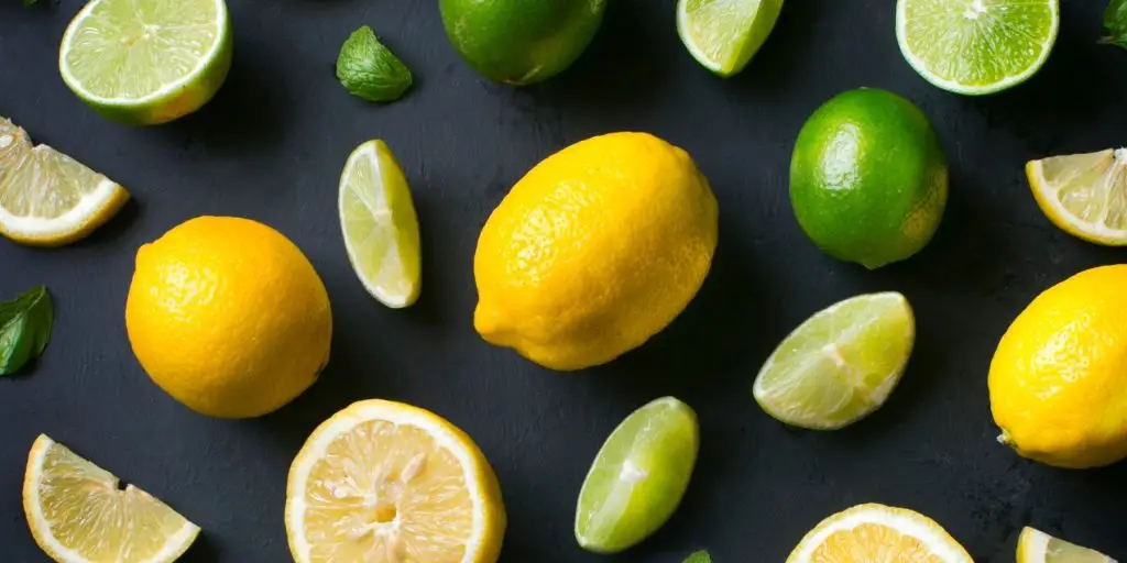 Fresh lemons and limes scattered on a dark background