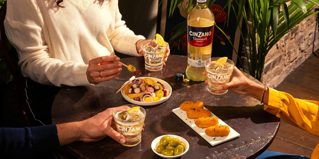 Friends enjoying Cinzano Bianco cocktails and snacks around a table