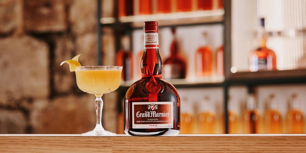 Sidecar cocktail next to a bottle of Grand Marnier served in a bar