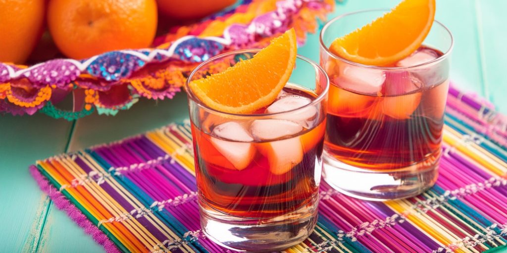 Two Oaxacan Negroni cocktails on a colourful placemat for Cinco de Mayo