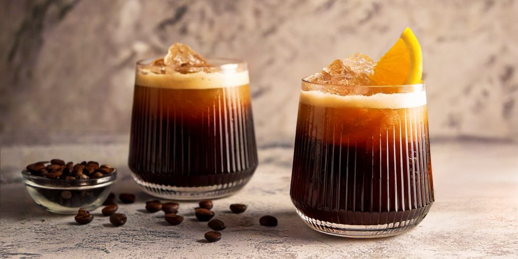 Two Carajillo Coffee cocktails with fresh orange garnish