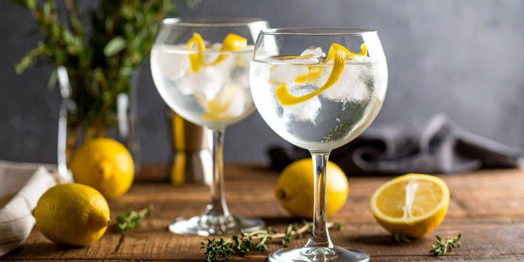 Close-up of two Gin and Tonic cocktails in ice-filled glasses with lemon peel garnish