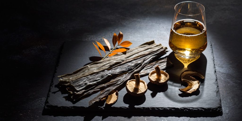 Dried seaweed, mushrooms and herbs on a slate board with a cocktail in background