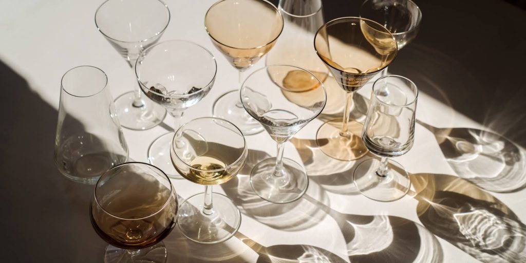 A collection of cocktail glasses on a white table with moody lighting