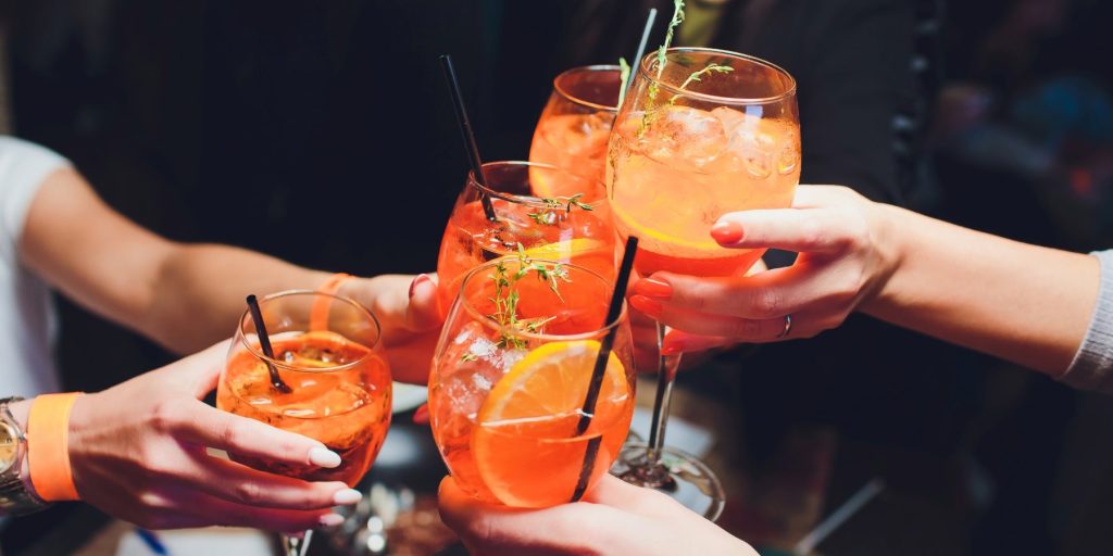 A group of friends toasting with Aperol spritz cocktails.