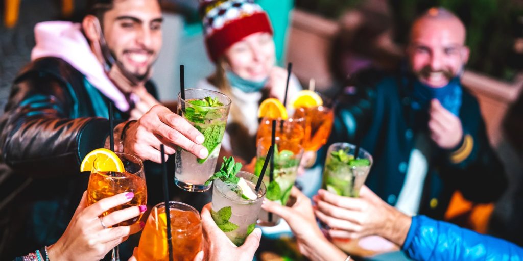 A group of friends in winter clothing toasting with Aperol cocktails.