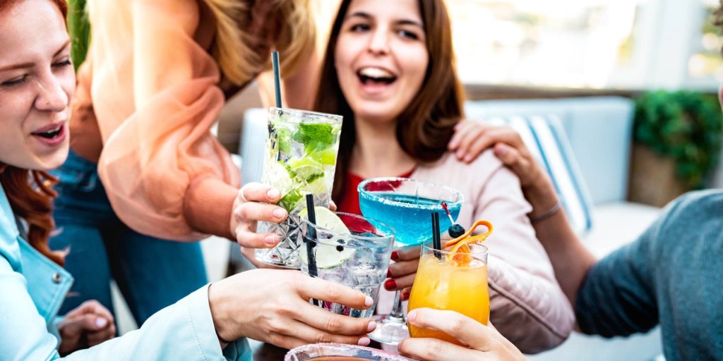 A smiling group of friends toasting with cocktails at happy hour.