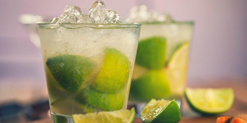Muddled Caipirinha in tumblers with lime wedges