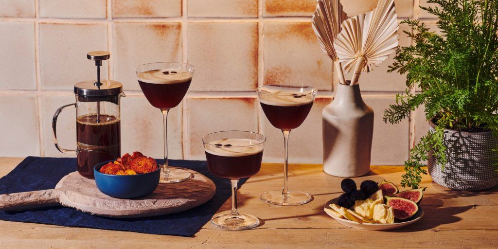 Front view of three decadent Espresso Martini cocktails served with sweet and savory snacks