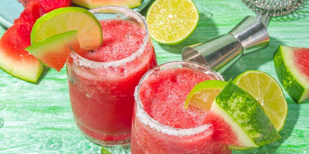 Close up top view of Watermelon Margaritas Cocktail garnished with lime wedges and watermelon slices
