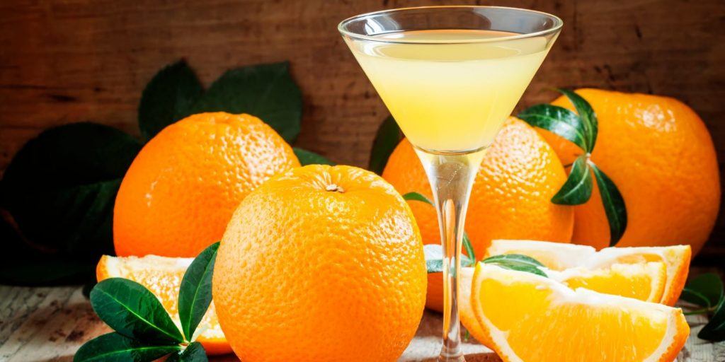 French Kiss Cocktail surrounded by fresh oranges