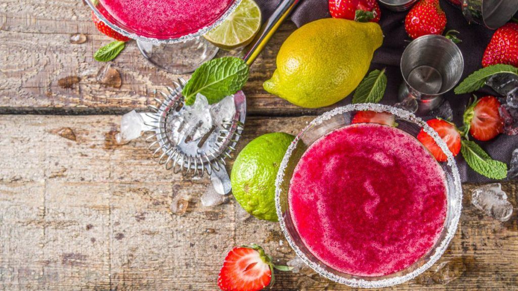 Brightly colored frozen strawberry margarita in salt rimmed glass