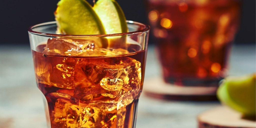 Close-up of Poison Apple cocktail on the rocks with sliced apple garnish