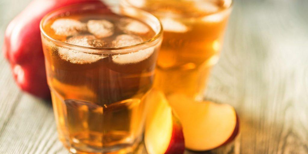 Close up of a glass of Bourbon Apple Cider Cocktail with fresh apple slices around it