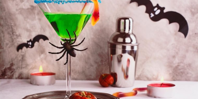 Bright green Witches Brew drink garnished with spiders, bats and snakes