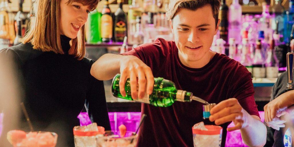 Guy pouring a drink while friends look on