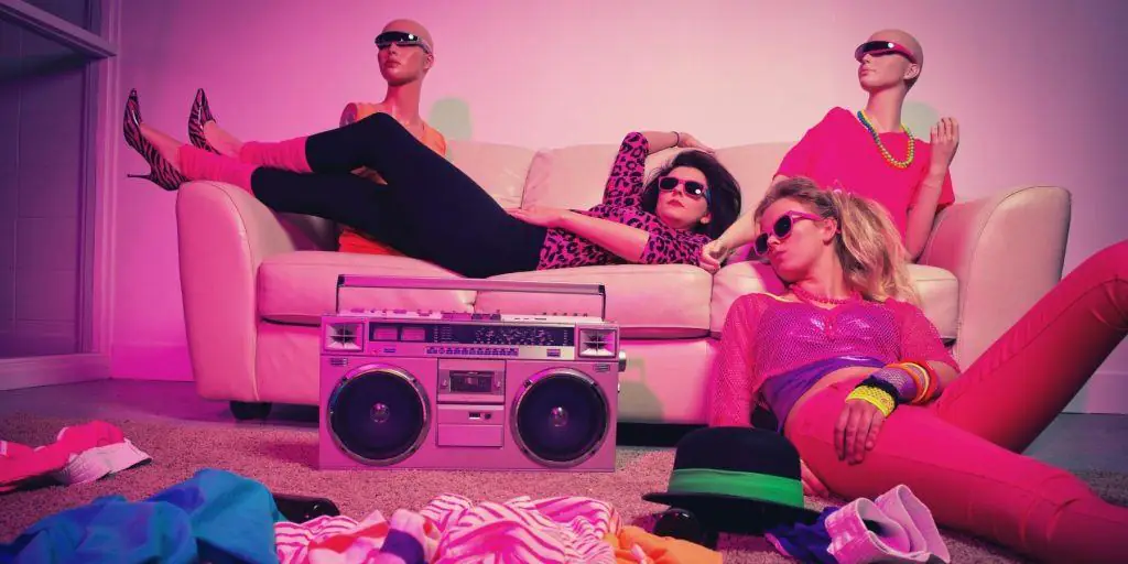 Two women in 80s fashion chilling out and listening to music on boombox