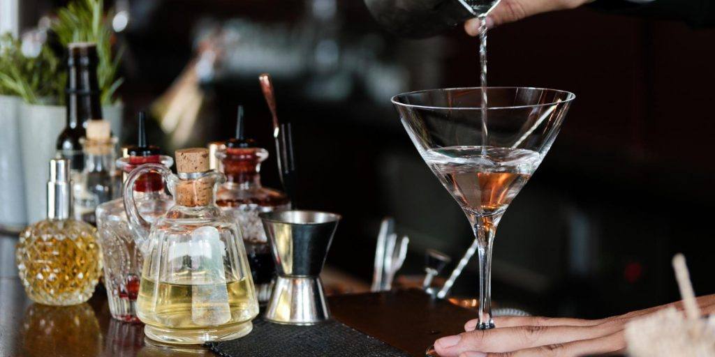 Bartender straining Martini into martini glass