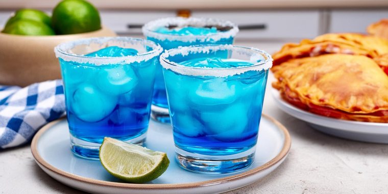 Three Blue Margarita cocktails served with empanadas in a kitchen setting