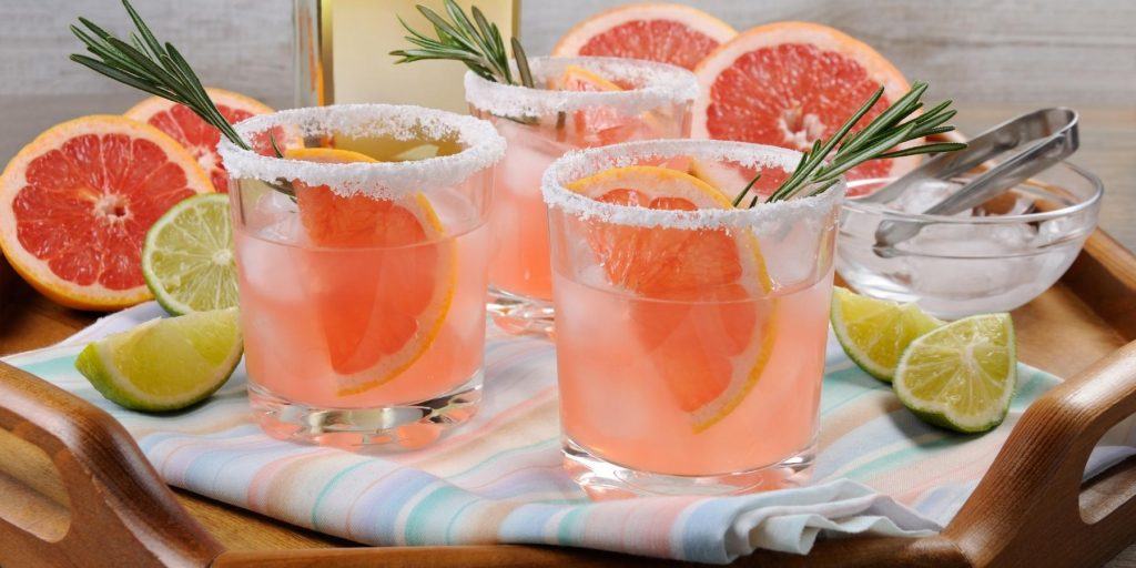 Close front view of a trio of refreshing pink paloma cocktails with grapefruit garnish