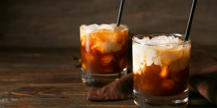 Two White Russian cocktails on a wooden board