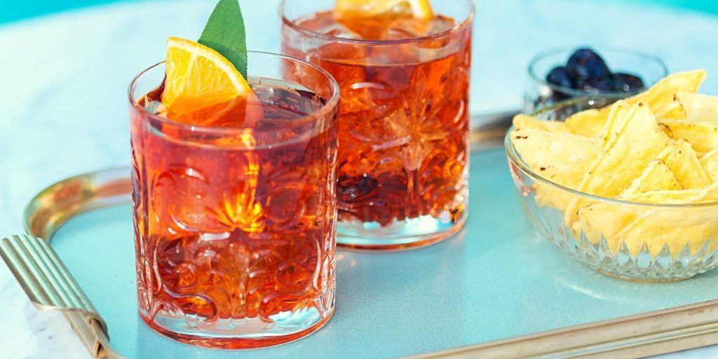 Bright Negroni cocktails served on a vintage tray with snacks