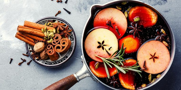 Top shot of mulled wine in a pot wit spices, citrus, herbs and fruit