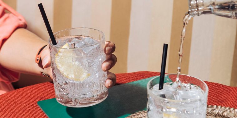 A woman's hand holding a tumbler filled with gin and tonic