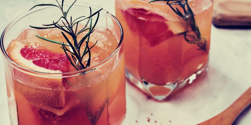 Two Micheganders garnished with grapefruit and rosemary on white