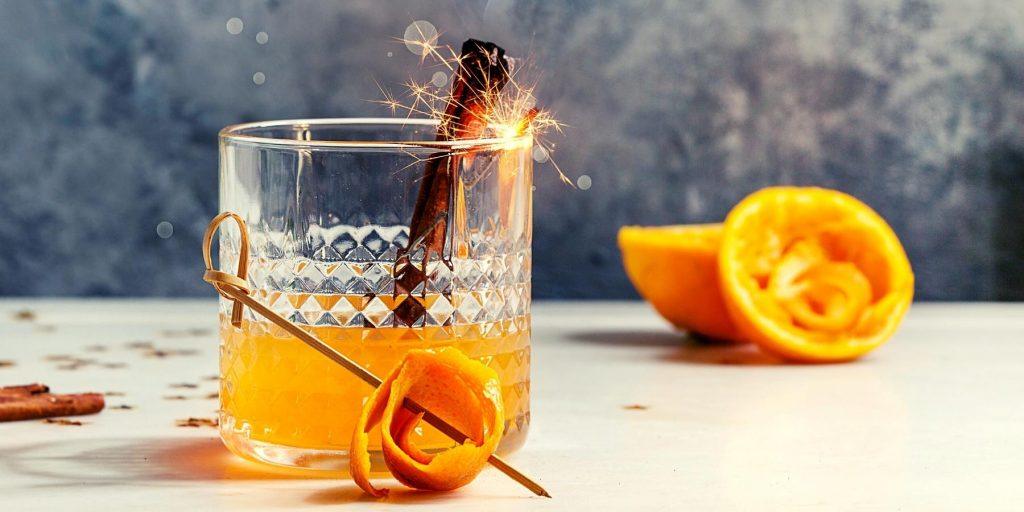 Orange cocktail in an Old Fashioned glass garnished with a sparkler