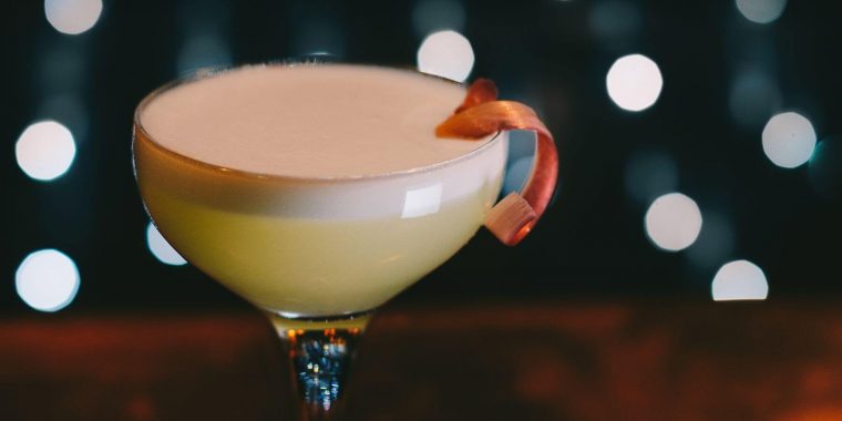 A white lady cocktail with frothy egg white top with sparkly background