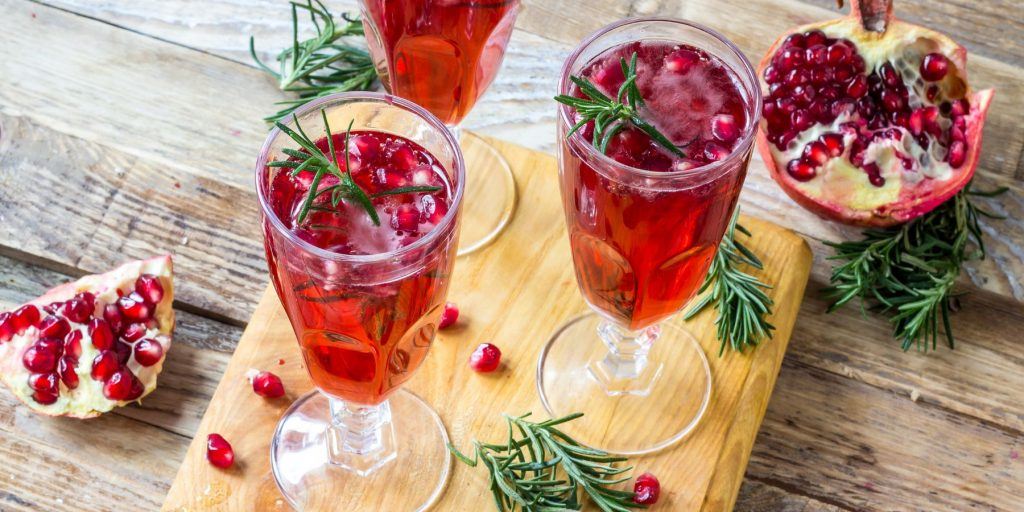 Close up top view of two Pomengrate Mimosas on a wooden table surrounded by fresh pomegranates