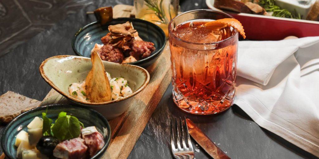 Negroni and small bowls of appetizers