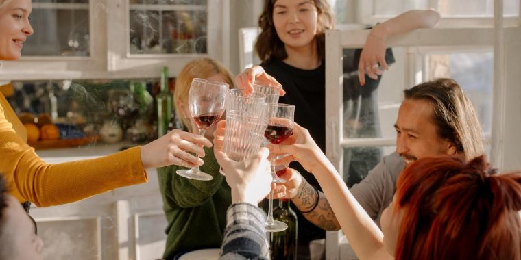 Friends clinking glasses together at kitchen table